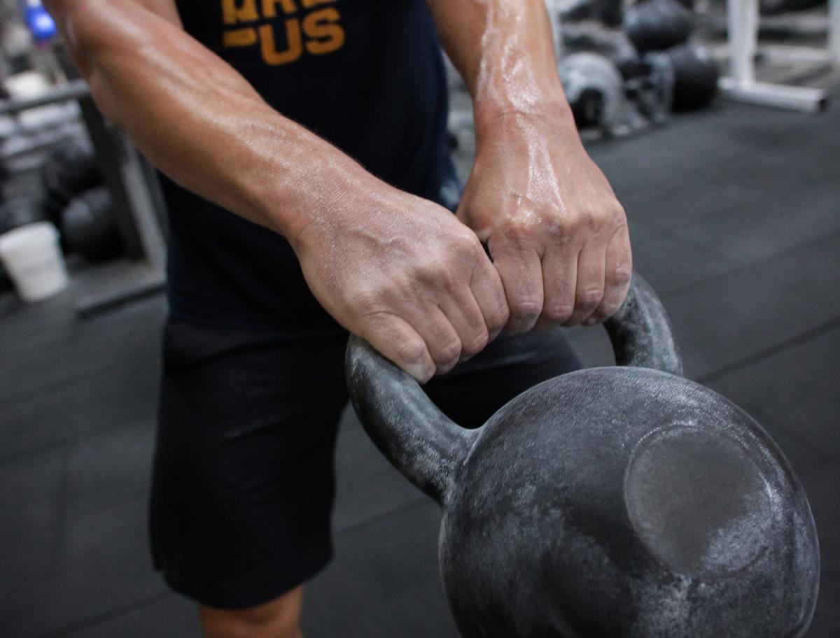 Chalked hands gripping a kettlebell